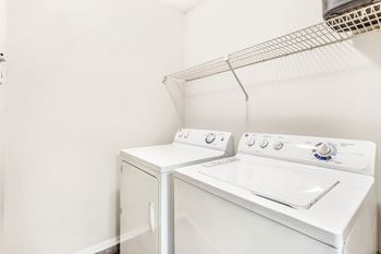 A white washing machine and dryer in a small laundry room. at Southpark Commons Apartment Homes, Charlotte, NC, 28210